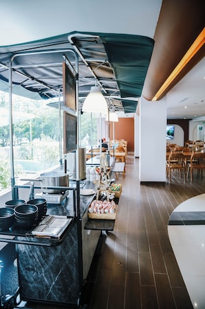 A restaurant with a counter, cooking equipment, and a view of the outdoors.