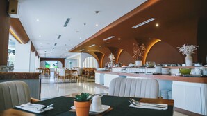 A modern restaurant with a high ceiling, recessed lighting, and a central island with a bar. - Omar Hotel (Tangerang)