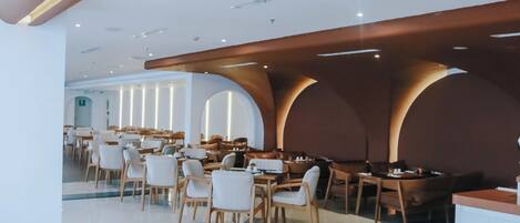 A spacious restaurant with high ceilings, wooden beams, and a modern interior design.