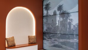A modern reception area with a curved bench, two patterned cushions, and a large digital display on the wall. - Omar Hotel (Tangerang)