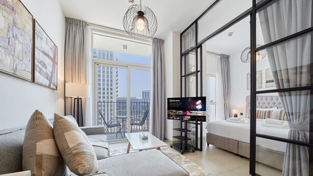 A modern hotel room with a sofa, a TV, a balcony, and a bed.