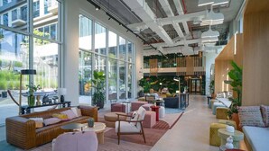 A spacious lobby with modern furniture, large windows, and a central seating area.