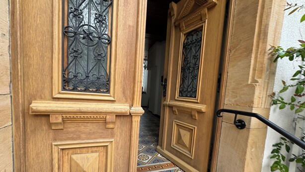 A wooden door with intricate metalwork and a patterned tile floor. - Vineyard View Attic Suite (Ruppertsberg)