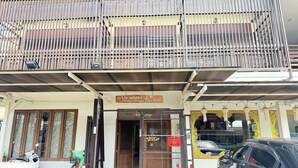 A building with a wooden balcony, a sign above the entrance, and a parked car.