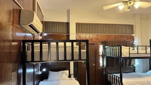 A dormitory room with bunk beds, a ceiling fan, and an air conditioning unit.