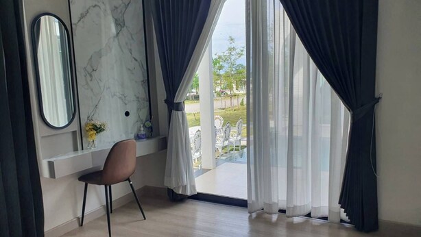Una habitación moderna con pared de mármol, un escritorio, una silla y ventanas amplias con cortinas.