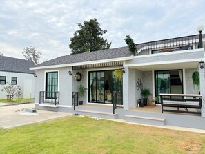 Una casa moderna de dos pisos con un porche cubierto, ventanas amplias y un pequeño jardín delantero.