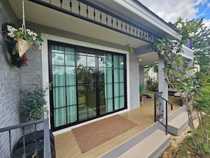 A modern house with a large sliding glass door, a covered porch, and a small staircase leading to the entrance.
