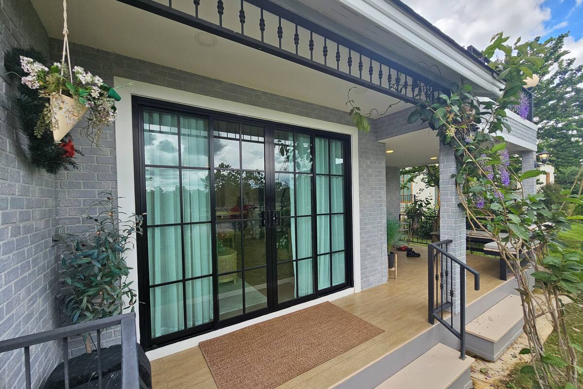 A modern house with a large sliding glass door, a covered porch, and a small staircase leading to the entrance.