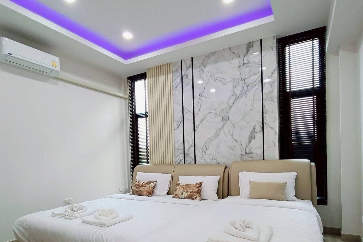 A modern bedroom with a large bed, marble wall, and ceiling lights.
