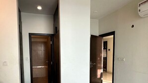 Een kamer met een bed, een deur naar een andere kamer en een aan het plafond bevestigde airconditioning.