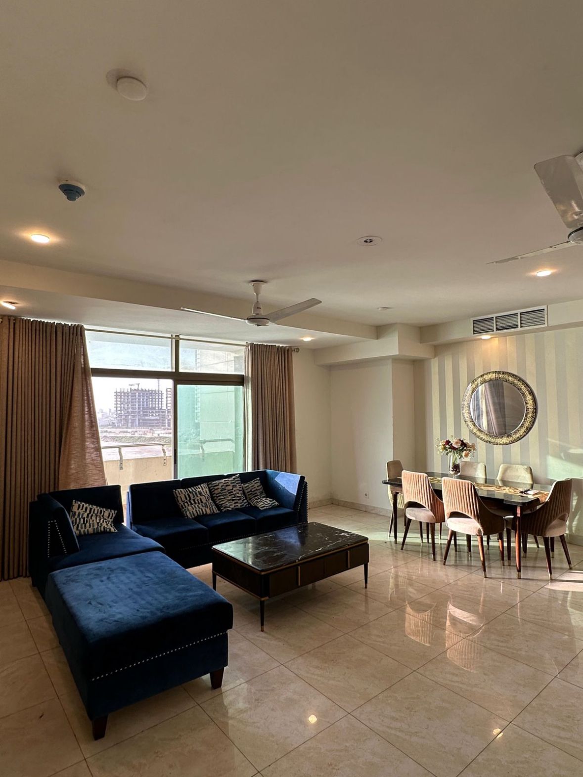 A spacious living room with a sofa set, a coffee table, and a dining area with chairs and a table.