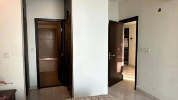 A room with a bed, a door leading to another room, and a ceiling-mounted air conditioning unit.
