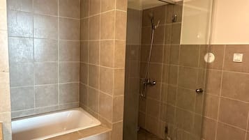 Ein Badezimmer mit Badewanne, Dusche und gefliesten Wänden.