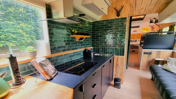 A compact kitchen with a black countertop, wooden cabinets, and a green-tiled backsplash. - Luxury tiny house with sauna in Lierneux (Lierneux)