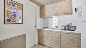 A modern kitchen with wooden cabinets, a sink, and a coffee maker. - Charming Suite Champs Elysees Trocadero (Paris)