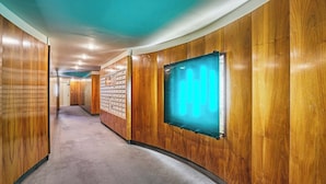 A hallway with wooden paneling, a carpeted floor, and a wall-mounted light fixture. - Charming Suite Champs Elysees Trocadero (Paris)