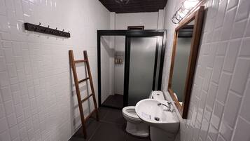 Un baño con paredes de azulejos blancos, una escalera de madera, un inodoro y un lavabo con espejo.