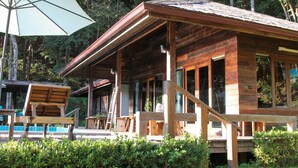 A wooden cabin with a porch, a table, and an umbrella.