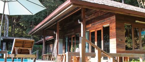 A wooden cabin with a porch, a table, and an umbrella.