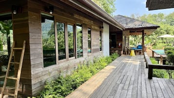 Eine Holzterrasse mit Pool, überdachter Sitzgelegenheit und einer Holzleiter.