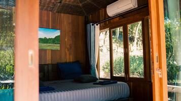 Een houten kamer met een bed, een raam en een airconditioning.