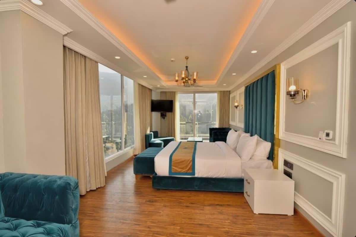 Une chambre d’hôtel spacieuse, dotée d’un grand lit, d’un coin salon et offrant une vue sur la ville.