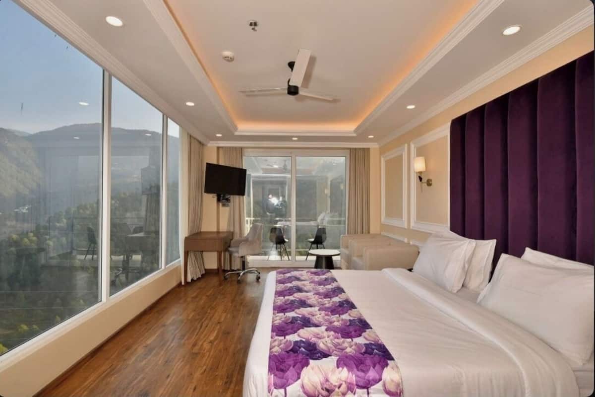 Une chambre d’hôtel avec un grand lit, un bureau, une chaise et un téléviseur.