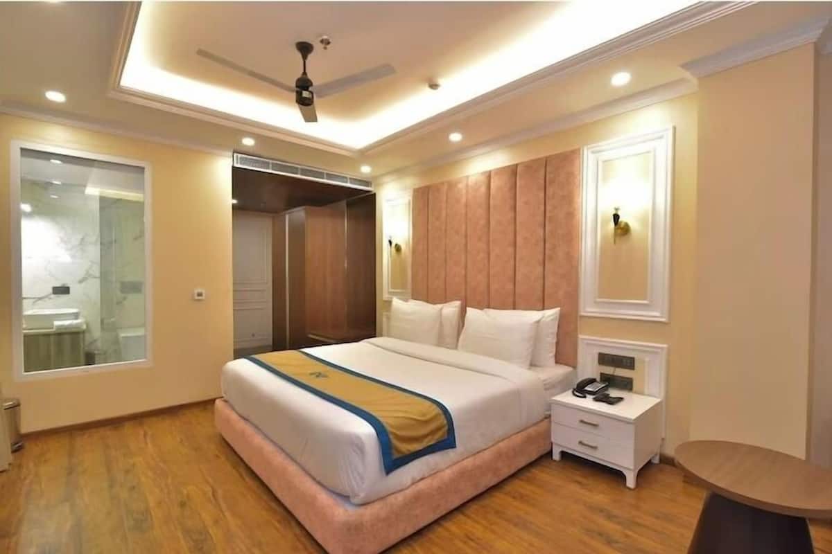 Une chambre d’hôtel avec un grand lit, une table de chevet et un ventilateur de plafond.