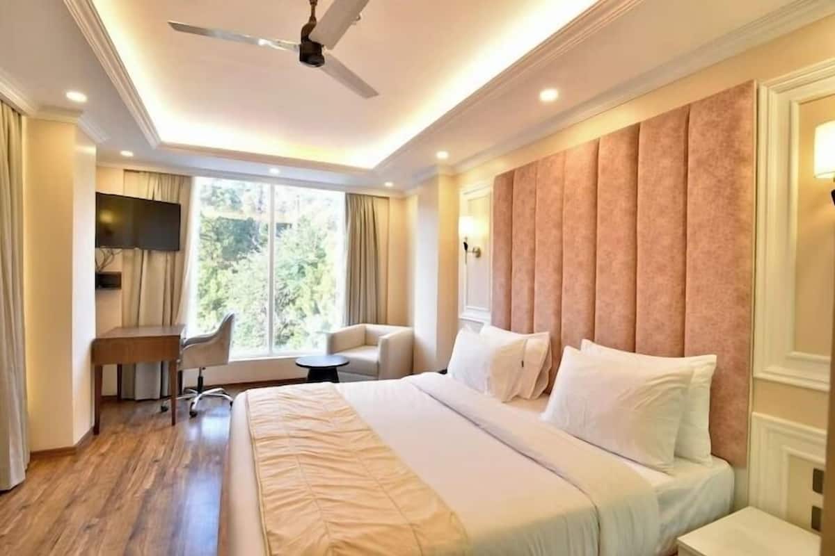 Une chambre d’hôtel avec un grand lit, un bureau, une chaise et un téléviseur.
