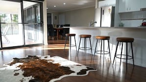 A modern kitchen with wooden flooring, a cowhide rug, and bar stools. - Spacious Retreat, Walk to Town (Denman)