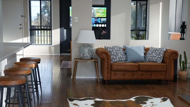 A spacious living room with a brown leather sofa, a cowhide rug, and wooden bar stools. - Spacious Retreat, Walk to Town (Denman)