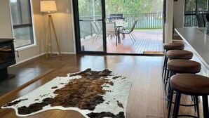 A spacious room with a large wooden floor, a cowhide rug, and a bar area with stools. - Spacious Retreat, Walk to Town (Denman)