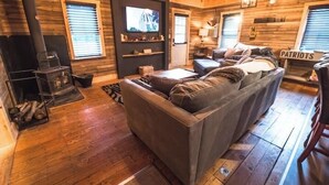 A cozy log cabin interior with a fireplace, a comfortable sofa, and a television. - The Overlook/Cozy 2 bed/Hot Tub/Wood Stove/Firepit (Carroll County)
