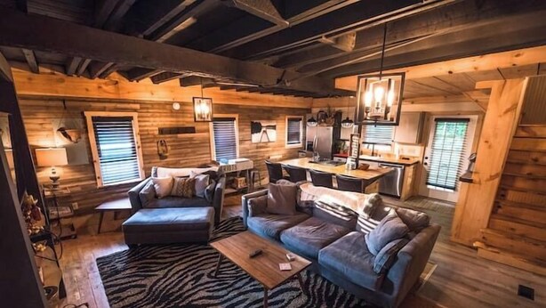 A cozy log cabin interior with a living area featuring a sofa, a coffee table, and a dining table. - The Overlook/Cozy 2 bed/Hot Tub/Wood Stove/Firepit (Carroll County)