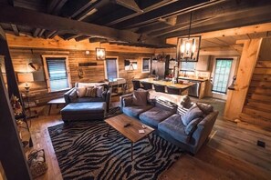 A cozy log cabin interior with a living area featuring a sofa, a coffee table, and a dining table. - The Overlook/Cozy 2 bed/Hot Tub/Wood Stove/Firepit (Carroll County)