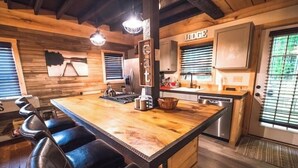 A kitchen with a large island, bar stools, and wooden walls. - The Overlook/Cozy 2 bed/Hot Tub/Wood Stove/Firepit (Carroll County)