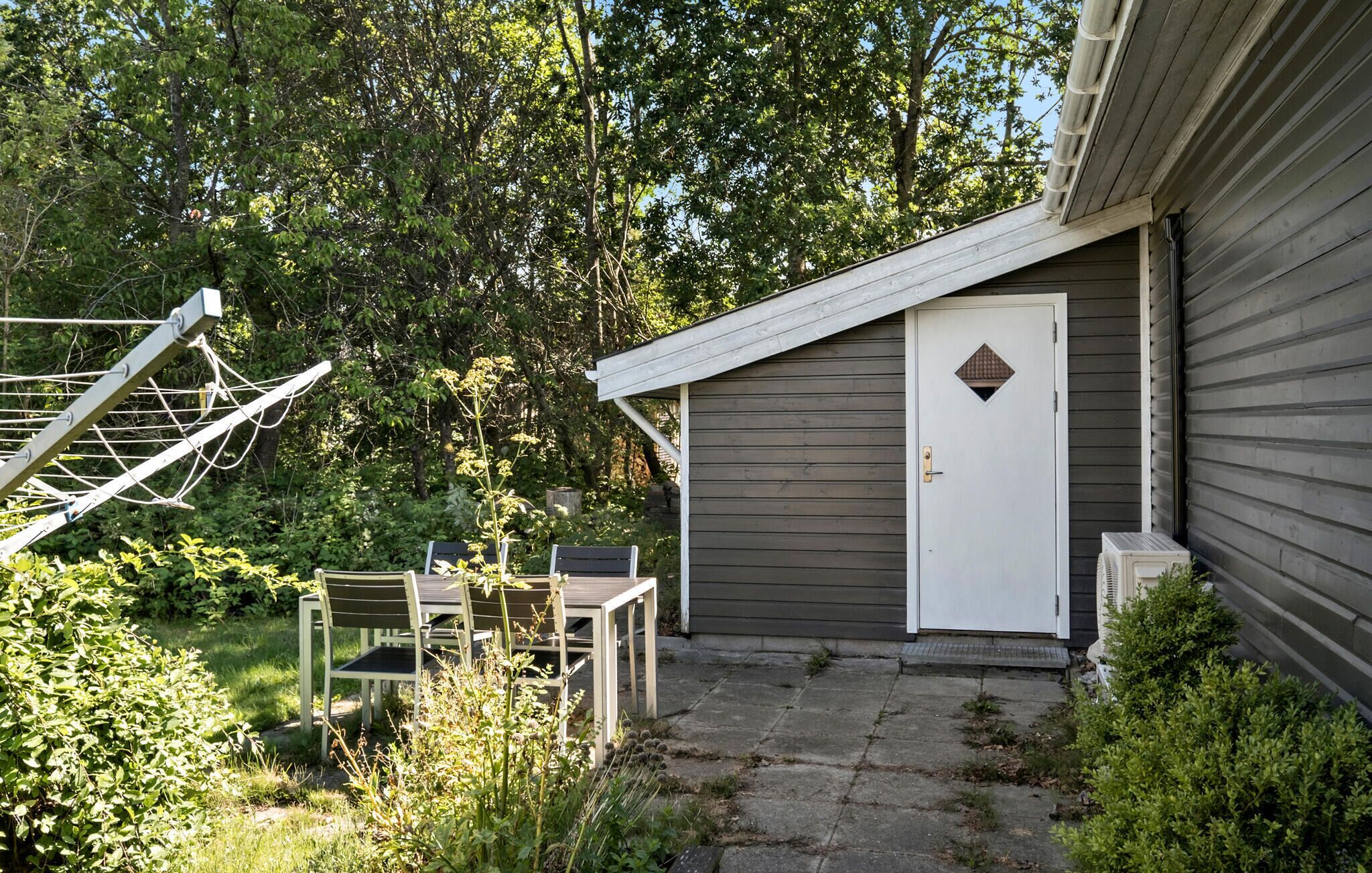 En boligejendom med en overdækket terrasse, en dør med et diamantformet vindue og et tørresnor.