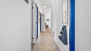 A hallway with white walls, blue doors, and a tiled floor.