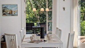 A dining area with a white table, black chairs, and a painting on the wall.