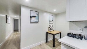 A modern kitchen with a coffee bar, wooden flooring, and minimalist decor.