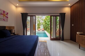 Un dormitorio con cama, vista a una piscina al aire libre y pared de madera.