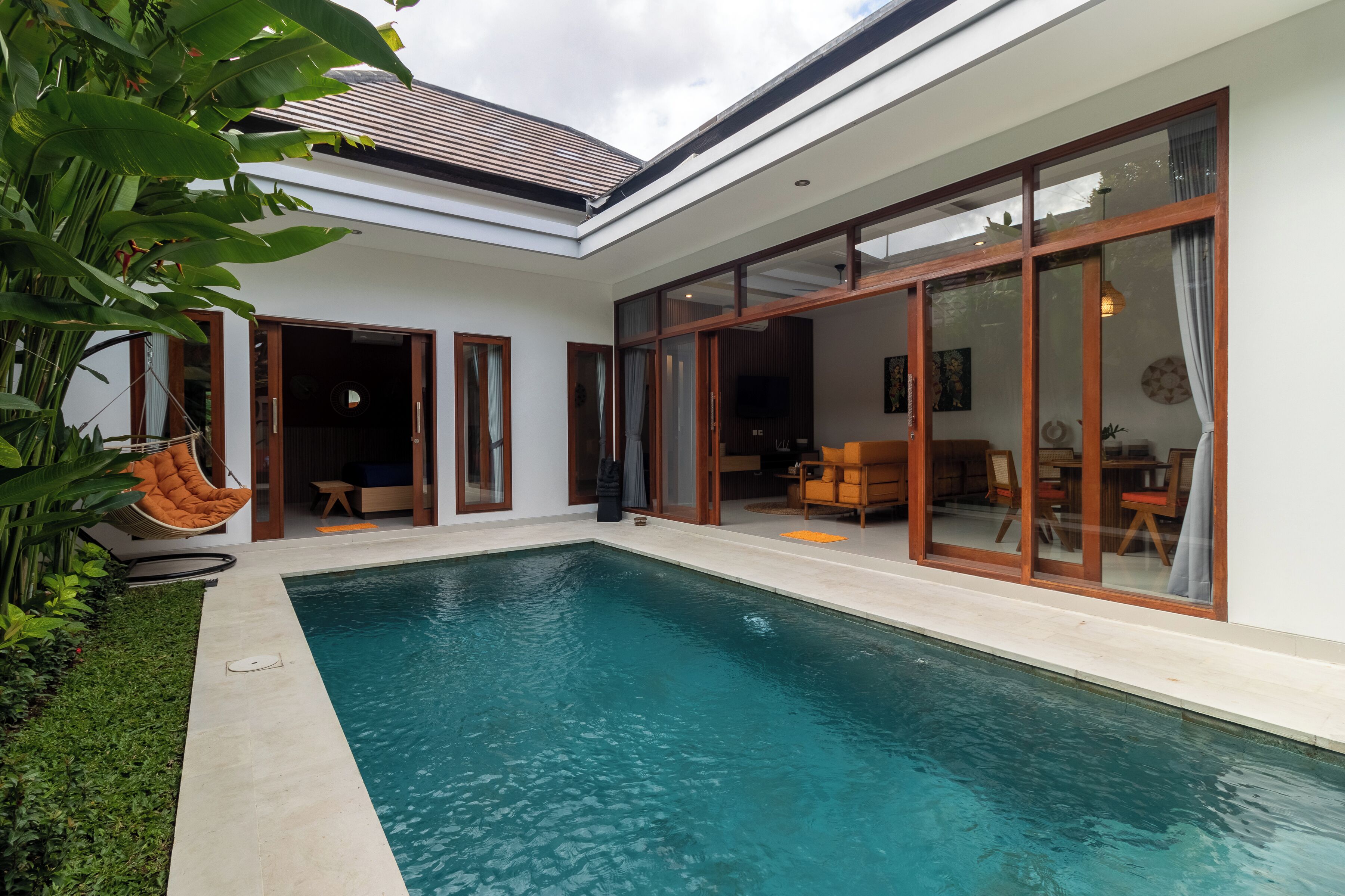 Una casa moderna con piscina, puertas correderas de vidrio grandes y un jardín cuidado.