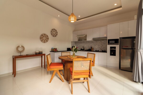 Una cocina moderna con armarios blancos, una mesa de comedor con sillas y una lámpara colgante.