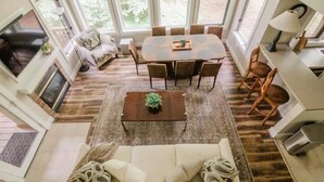 A spacious living area with a large dining table surrounded by chairs, a sofa, and a coffee table. - ModCabin Escape - Ski In/Out +Heated pool Avail! (Boyne Falls)
