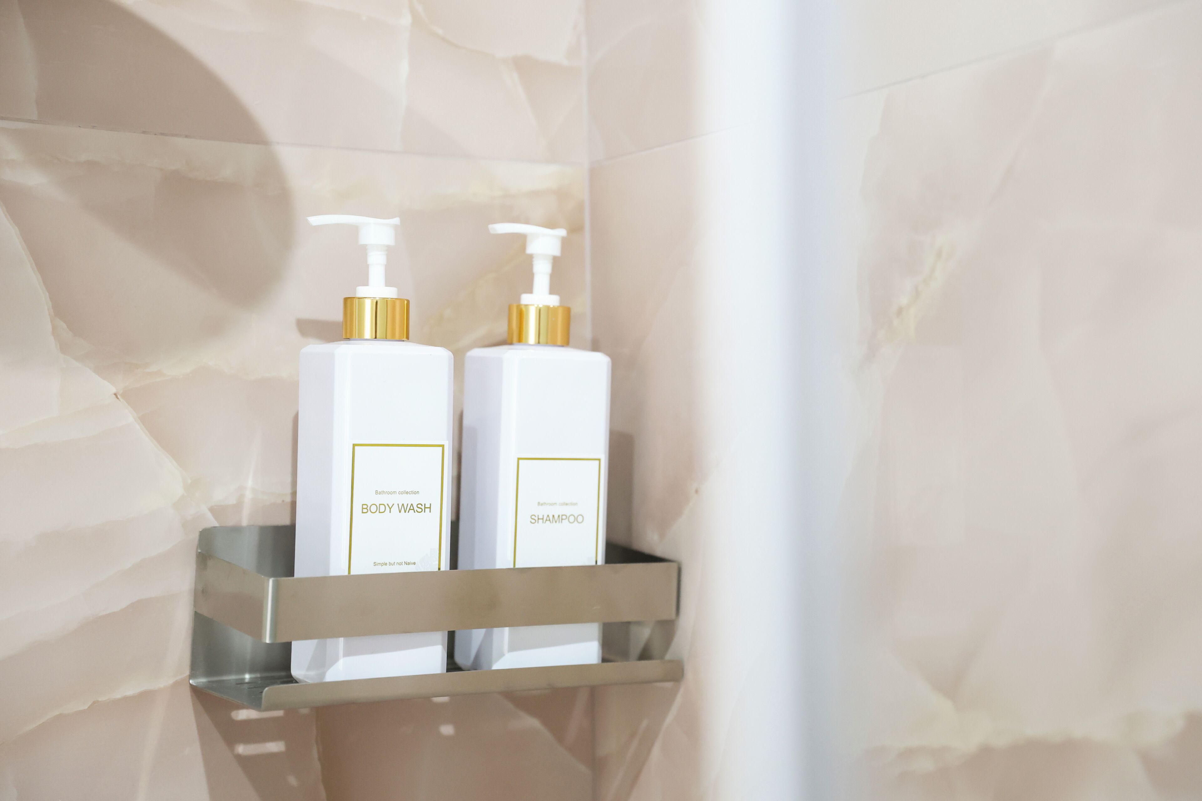 A bathroom shelf with two bottles of body wash and shampoo.