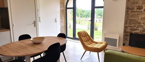 Un comedor con una mesa redonda de madera, sillas negras, un sillón amarillo y un sofá verde.
