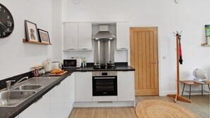 Une cuisine moderne avec des meubles blancs, un four Bosch, un micro-ondes et un évier.