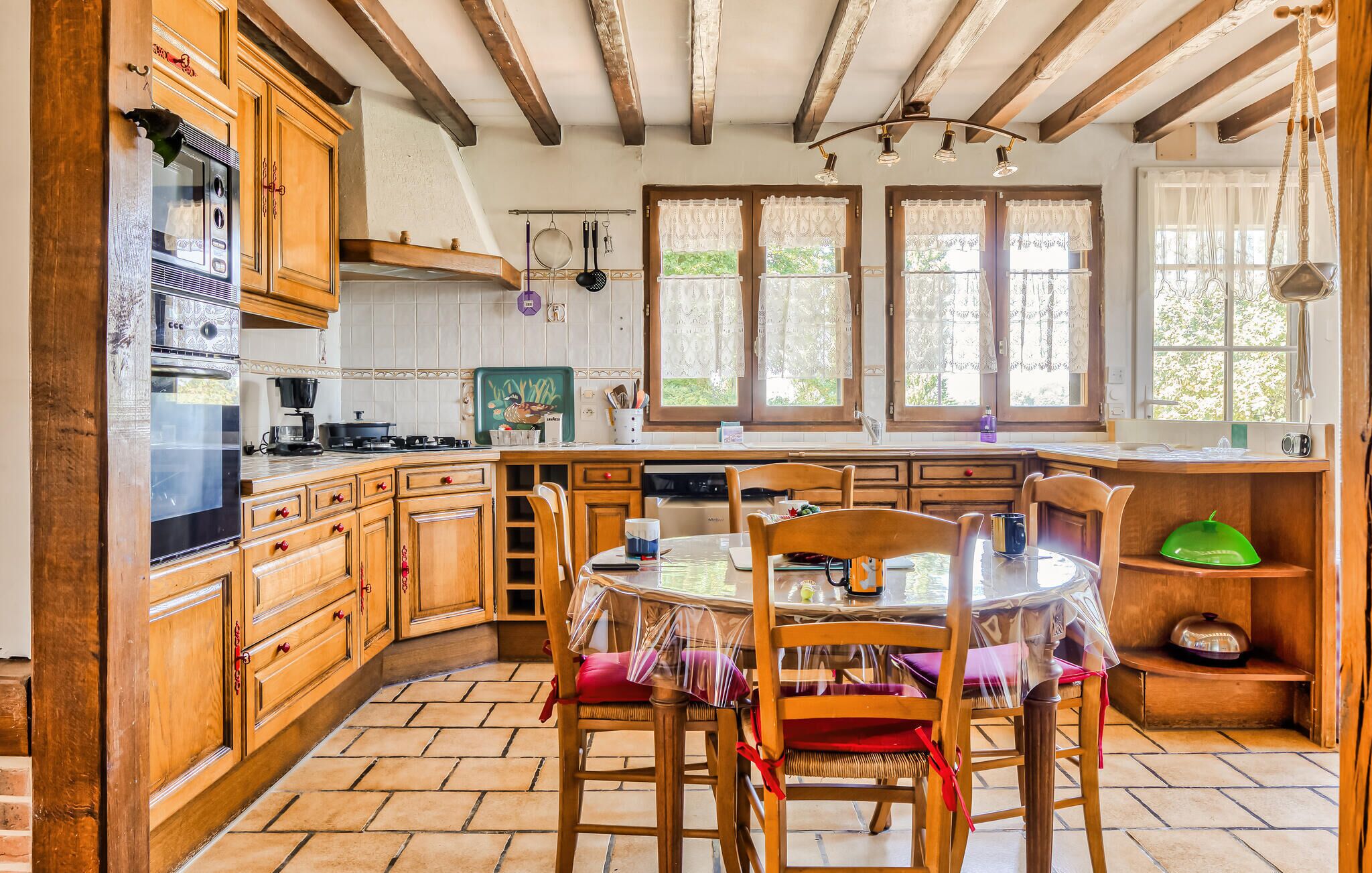 A kitchen with wooden cabinets, a stove, and a dining area with a table and chairs.