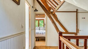 A wooden staircase leading to a bedroom with a bed and a window.